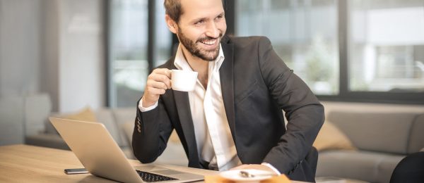 man-holding-white-teacup-in-front-of-gray-laptop-842567